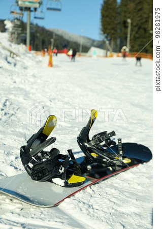 Empty snowboard on ski slope in sunny day Empty snowboard on ski slope in sunny day 98281975