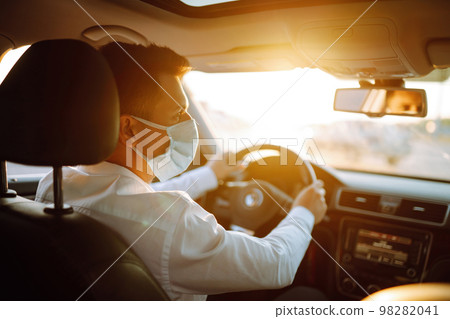 Man driving a car wearing on a medical mask during an epidemic, a driver- taxi in a mask. Covid-2019 98282041
