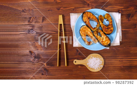 Tasty salmon steak close up, pan with herbs and sea salt. Seafood. Cooking concept. Copy space 98287392