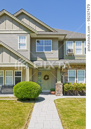 Entrance of family house with concrete pathway over green lawn 98287479