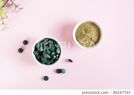 Detox products. Spirulina seaweed in pills and matcha tea powder in bowls on a pink. Top view 98287591