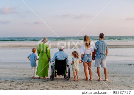 Rear view of three geneartions family with little kids enjoying time at sea in exotic country. Rear view of three geneartions family with little kids enjoying time at sea in exotic country. 98287737