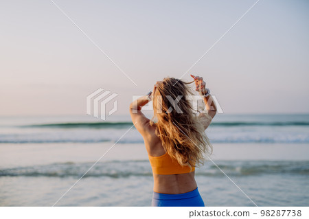 Rear view of young sportive woman at beach. Rear view of young sportive woman at beach. 98287738