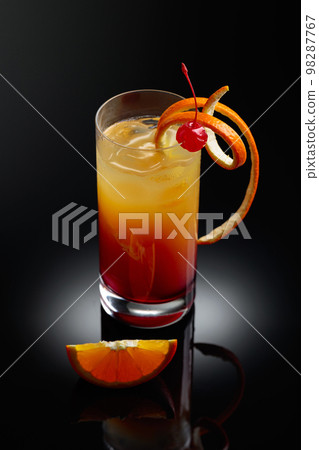 Cocktail tequila sunrise on a black reflective background. Cocktail tequila sunrise on a black reflective background. 98287767