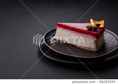 Delicious sweet cheesecake with raspberry jam on a black ceramic plate Delicious sweet cheesecake with raspberry jam on a black ceramic plate 98287834