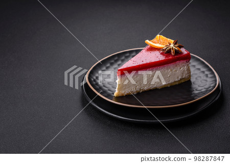 Delicious sweet cheesecake with raspberry jam on a black ceramic plate Delicious sweet cheesecake with raspberry jam on a black ceramic plate 98287847