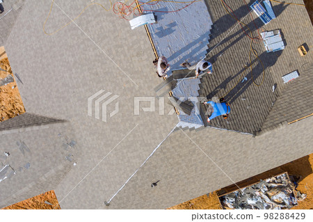 Construction roofing worker on roof the house installed new shingles 98288429