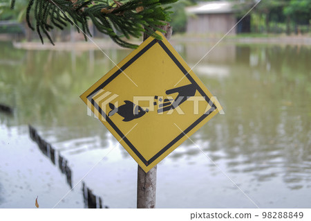A pillar with a yellow sign indicates this area is for fish feeding. 98288849