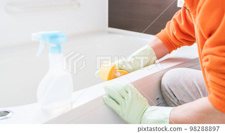 Middle-aged man cleaning the bathtub in the bathroom Middle-aged man cleaning the bathtub in the bathroom 98288897
