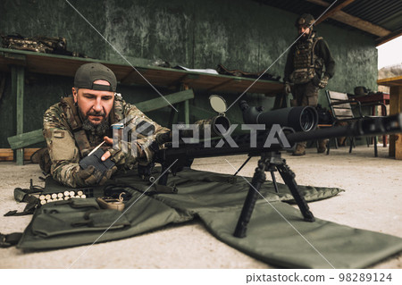 Soldier in camouflage preparing the rifle for shooting 98289124
