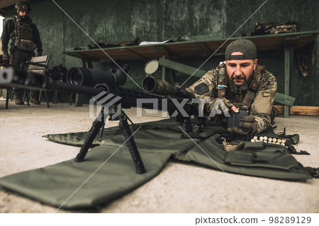 Soldier in camouflage preparing the rifle for shooting 98289129