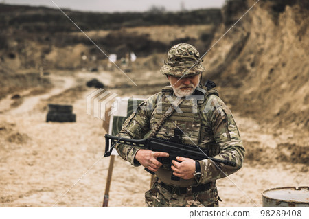 Mature soldier with a rifle in hands on a shooting range 98289408