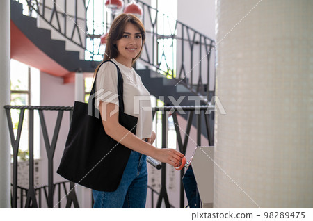 Smiling woman standing at the stairs and looking contented 98289475