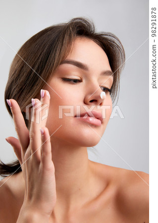 Touch. Emotional young beautiful girl with well-kept skin doing face cosmetology procedures isolated over light background. Beauty, art, emotions, spa, skincare concept Touch. Emotional young beautiful girl with well-kept skin doing face cosmetology procedures isolated over light background. Beauty, art, emotions, spa, skincare concept 98291878