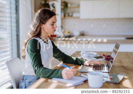 Young woman having distance education in her apartment. Young woman having distance education in her apartment. 98292151
