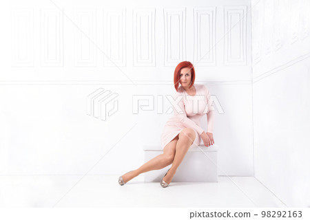 attractive woman in a pink dress in a room with white walls attractive woman in a pink dress in a room with white walls 98292163