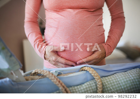 Close-up of pregnant woman preparing for baby, stroking her belly. 98292232