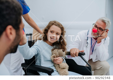 Happy doctors with clown red noses taking care about little girl. 98292348