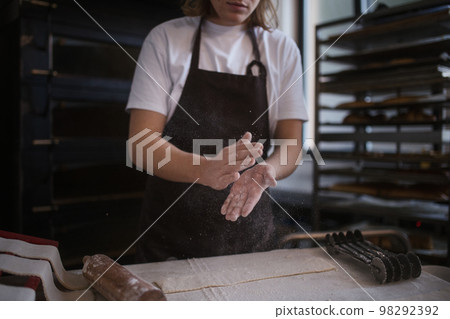 Close-up of baker preparing pastries in bakery. 98292392