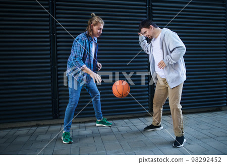 Man with down syndrome playing basketball outdoor with his friend. Concept of friendship and integration people with disability into society. Man with down syndrome playing basketball outdoor with his friend. Concept of friendship and integration people with disability into society. 98292452
