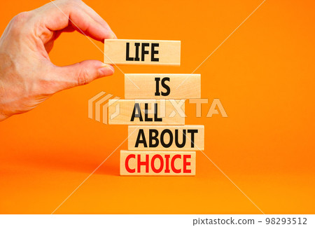 Choice and life symbol. Concept words Life is all about choice on wooden blocks. Beautiful orange table orange background. Businessman hand. Business choice and life concept. Copy space. 98293512
