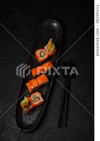 Shrimp sushi roll and chopsticks on black concrete background 98294212