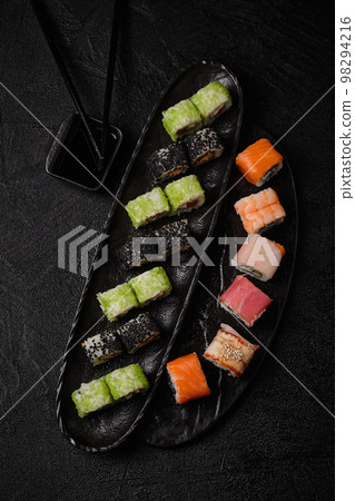 Different kind of sushi roll, soy sauce and chopsticks on black background Different kind of sushi roll, soy sauce and chopsticks on black background 98294216