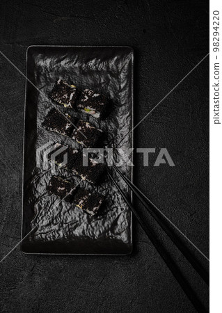 Black sushi roll on black plate on black background Black sushi roll on black plate on black background 98294220