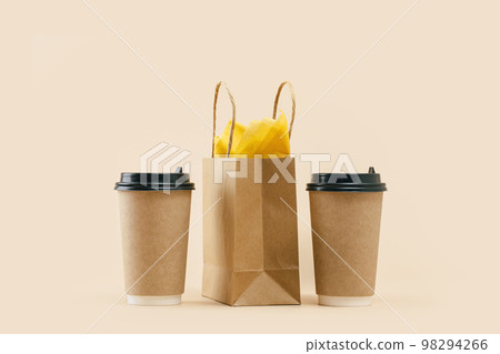 Takeaway two paper coffee cups with lunch bag on beige. Snack delivery service. Coffee to go. Grab and go or carry out beverage. Disposable mockup packaging. pair. Minimal 98294266