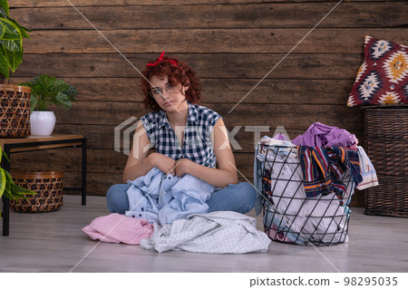 The tedious job of selecting shirts for washing. A girl with curly hair. 98295035