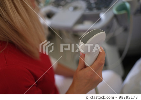 Female doctor holds ultrasound scanner device for examining patient in her hand. 98295178