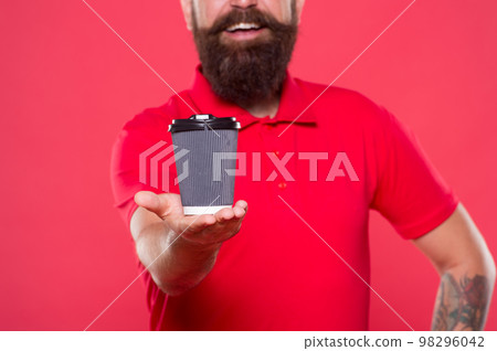 brutal hipster red uniform. happy barista fresh coffee. try take away coffee. best quality of cafe waiter. good morning coffee to go. energy concept. bearded man drink from paper cup 98296042