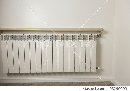 The concept of central heating in winter. The metal radiator of the heater hangs on the wall in the house. 98296093