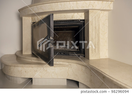 The glass door of the fireplace is open. Modern marble fireplace with glass. The glass door of the fireplace is open. Modern marble fireplace with glass. 98296094
