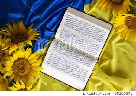 Bible (Holy Writ) and sunflowers on background of flag of Ukraine. Bible (Holy Writ) and sunflowers on background of flag of Ukraine. 98296343