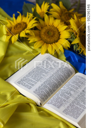 Bible (Holy Writ) and sunflowers on background of flag of Ukraine. 98296346