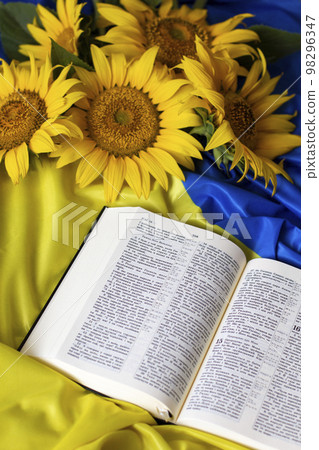 Bible (Holy Writ) and sunflowers on background of flag of Ukraine. Bible (Holy Writ) and sunflowers on background of flag of Ukraine. 98296347