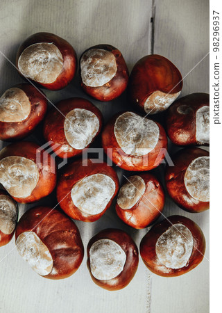 Ripe chestnuts on old wooden table and sack napkin close up with copy space. Raw Chestnuts for Christmas 98296937