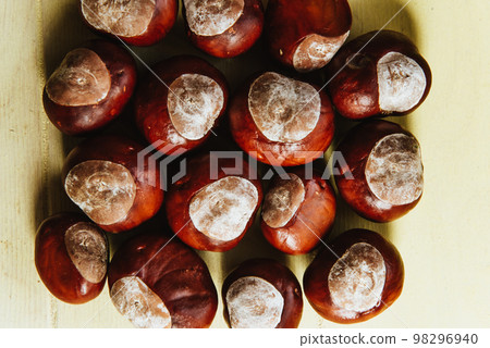 Ripe chestnuts on old wooden table and sack napkin close up with copy space. Raw Chestnuts for Christmas 98296940