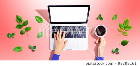 Person using a laptop computer with green leaves 98298161