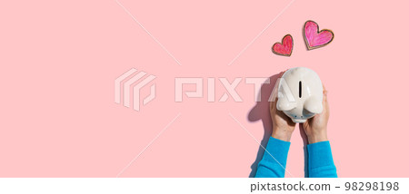 Person holding piggy bank with hearts Person holding piggy bank with hearts 98298198