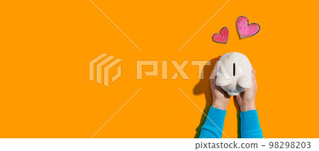 Person holding piggy bank with hearts 98298203