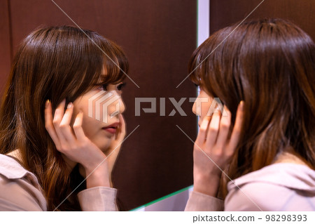 Woman checking her makeup in the mirror 98298393