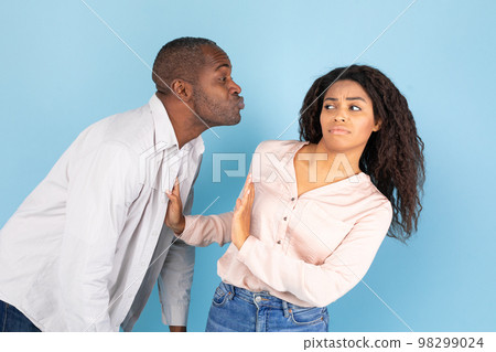 Friendzone concept. Disgusted black young woman avoiding unwanted kiss from middle aged man 98299024