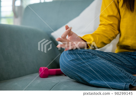 Young woman practise yoga and meditation in lotus position, mindfulness lifestyle, Asian female sits on sofa at home and chilling do yoga exercise with couch lotus pose eyes closed, healthy care Young woman practise yoga and meditation in lotus position, mindfulness lifestyle, Asian female sits on sofa at home and chilling do yoga exercise with couch lotus pose eyes closed, healthy care 98299145