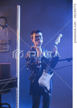 Punk rocker clenching fists and being aggressive, acting violent and crazy before singing heavy metal live performance. Alternative musical artist making fight threat and being mad. 98299773