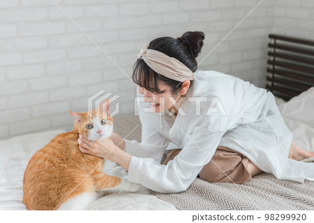 Owner's Asian woman playing with cats and pets in the bedroom (face, pajamas) Owner's Asian woman playing with cats and pets in the bedroom (face, pajamas) 98299920