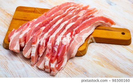 Close up of raw bacon steaks on wooden surface 98300160