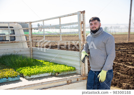 Confident young farmer near truck with vegetable seedlings Confident young farmer near truck with vegetable seedlings 98300188