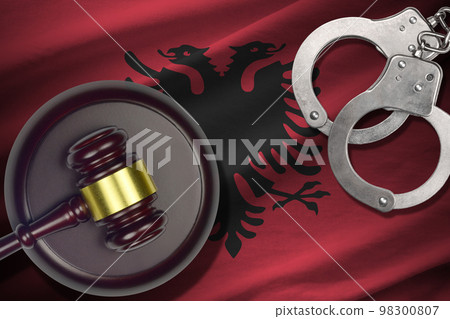 Albania flag with judge mallet and handcuffs in dark room. Concept of criminal and punishment, background for judgement topics Albania flag with judge mallet and handcuffs in dark room. Concept of criminal and punishment, background for judgement topics 98300807